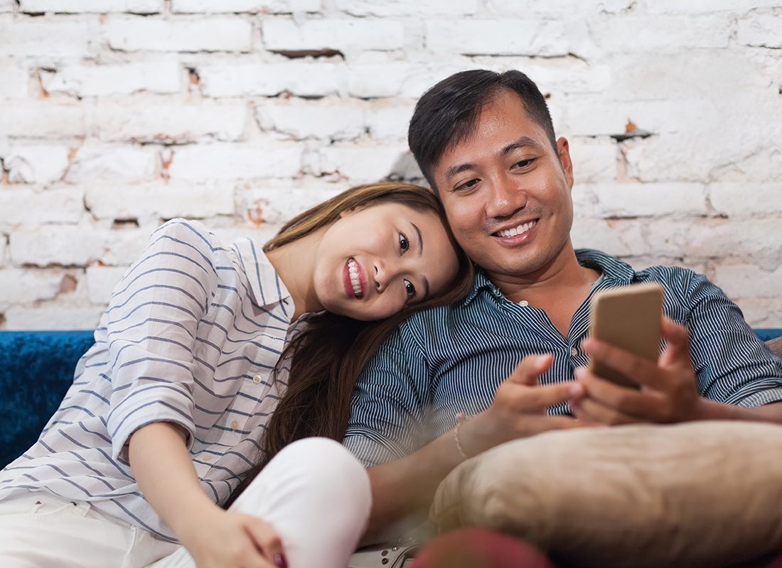 Read Our Reviews - Couple Cuddling on Their Couch Reading on a Phone
